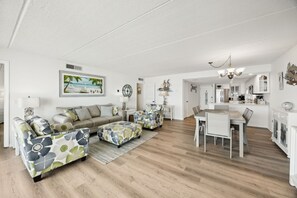 Ein modernes Wohnzimmer mit einer Sofagarnitur, einem Esstisch und einer Küchenzeile.