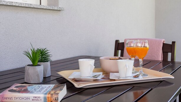 Une table avec un livre, un bol de biscuits, un verre de jus d’orange et une tasse.