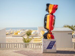 Una scultura intitolata "26 Sculpture Link" dell'artista Laurence Jenkell, posizionata su un piedistallo bianco con vista sulla spiaggia.