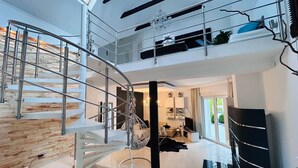 Un interior moderno con una escalera de caracol, una araña y vistas al exterior.