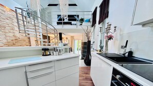 Una cocina moderna con armarios blancos, una estufa negra y piso de madera.