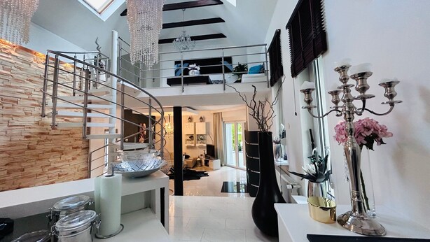 Un interior moderno con una escalera de caracol, una araña y un candelabro.