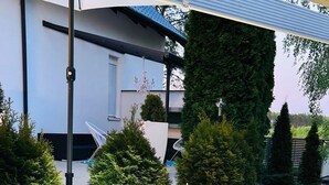 Un espacio exterior moderno con un sendero curvo, una zona de estar circular con luces iluminadas y arbustos y árboles cuidadosamente dispuestos.