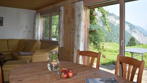 A wooden interior with a dining table, chairs, and a sofa.