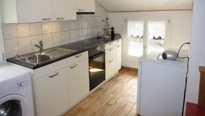 A compact kitchen with white cabinets, a stainless steel sink, a built-in oven, and a washing machine.