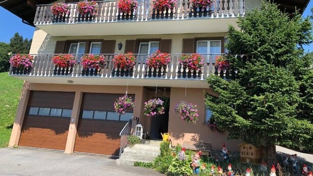 Ein zweistöckiges Gebäude mit einem Balkon, der mit Blumenkästen geschmückt ist.
