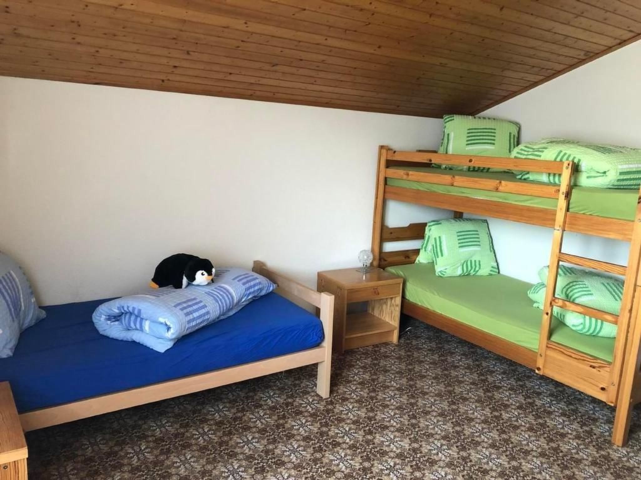 A bunk bed room with a single bed and a nightstand.