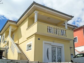 Ein zweistöckiges Gebäude mit Balkon, Treppe und einer Tür mit Glasverkleidung.