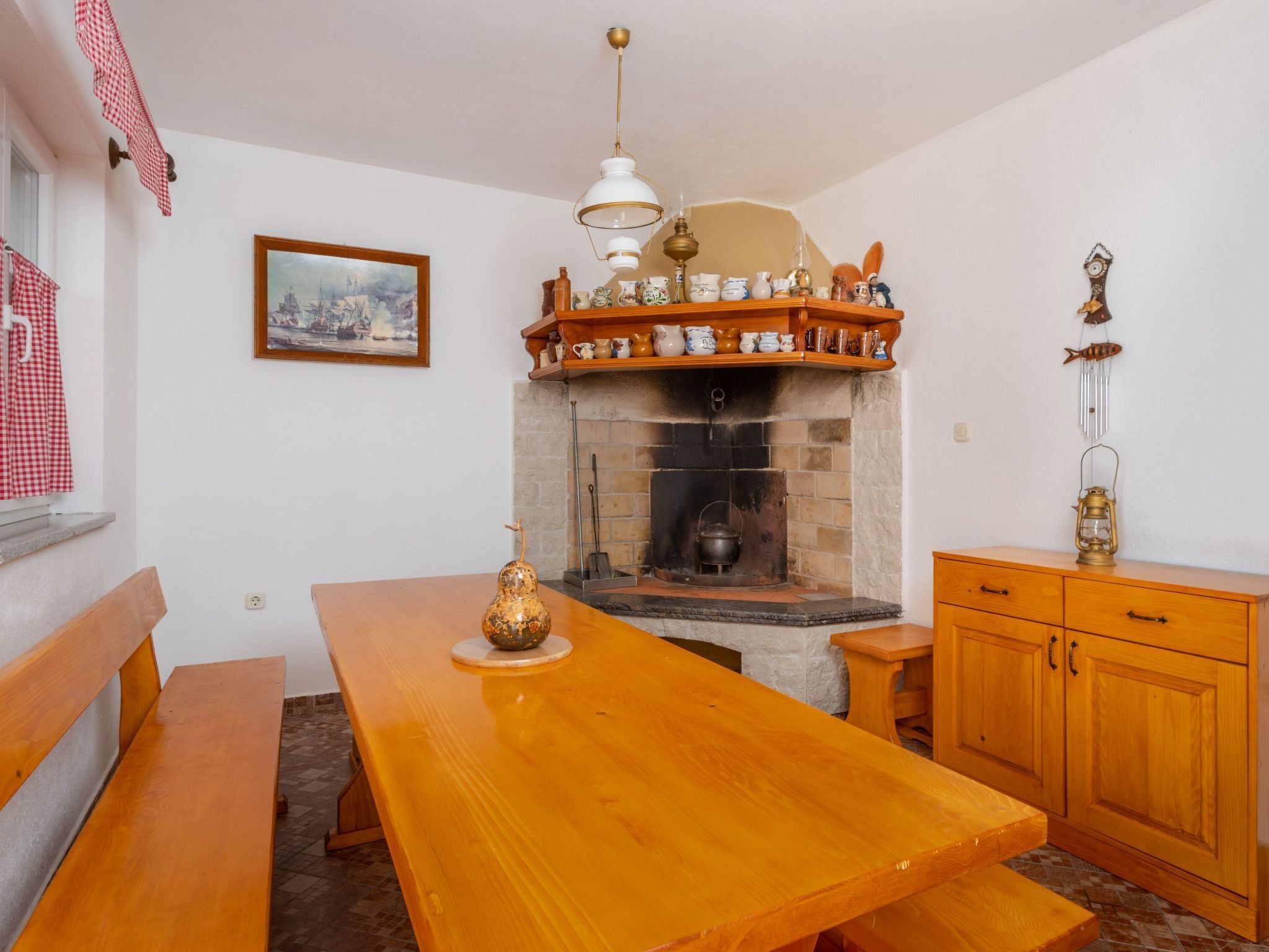Una cocina acogedora con una mesa de madera, una chimenea y un estante con diversos utensilios de cocina.