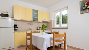 Une cuisine avec des meubles de couleur jaune, une table blanche et des chaises.