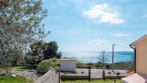 Une piscine avec vue sur la mer, entourée de murs de pierre et de verdure.