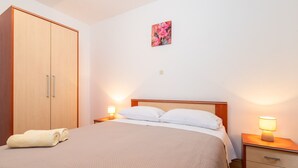 Une chambre à coucher comprenant un lit, deux tables de chevet avec des lampes, une armoire et un tableau accroché au mur.