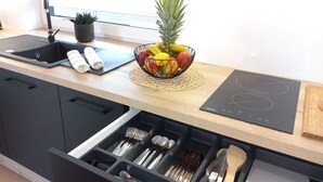 Una cocina moderna con encimera negra, frutero, pileta y horno empotrado.