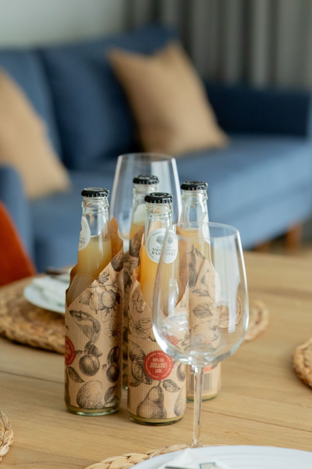 A table with bottles and a wine glass, set on a wooden surface with woven placemats.