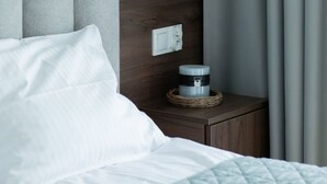 Una habitación de hotel moderna con cama, mesita de noche, lámpara de pared y cortina.