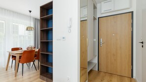 Una habitación moderna con zona de comedor, estanterías integradas, armario y una puerta con picaporte.