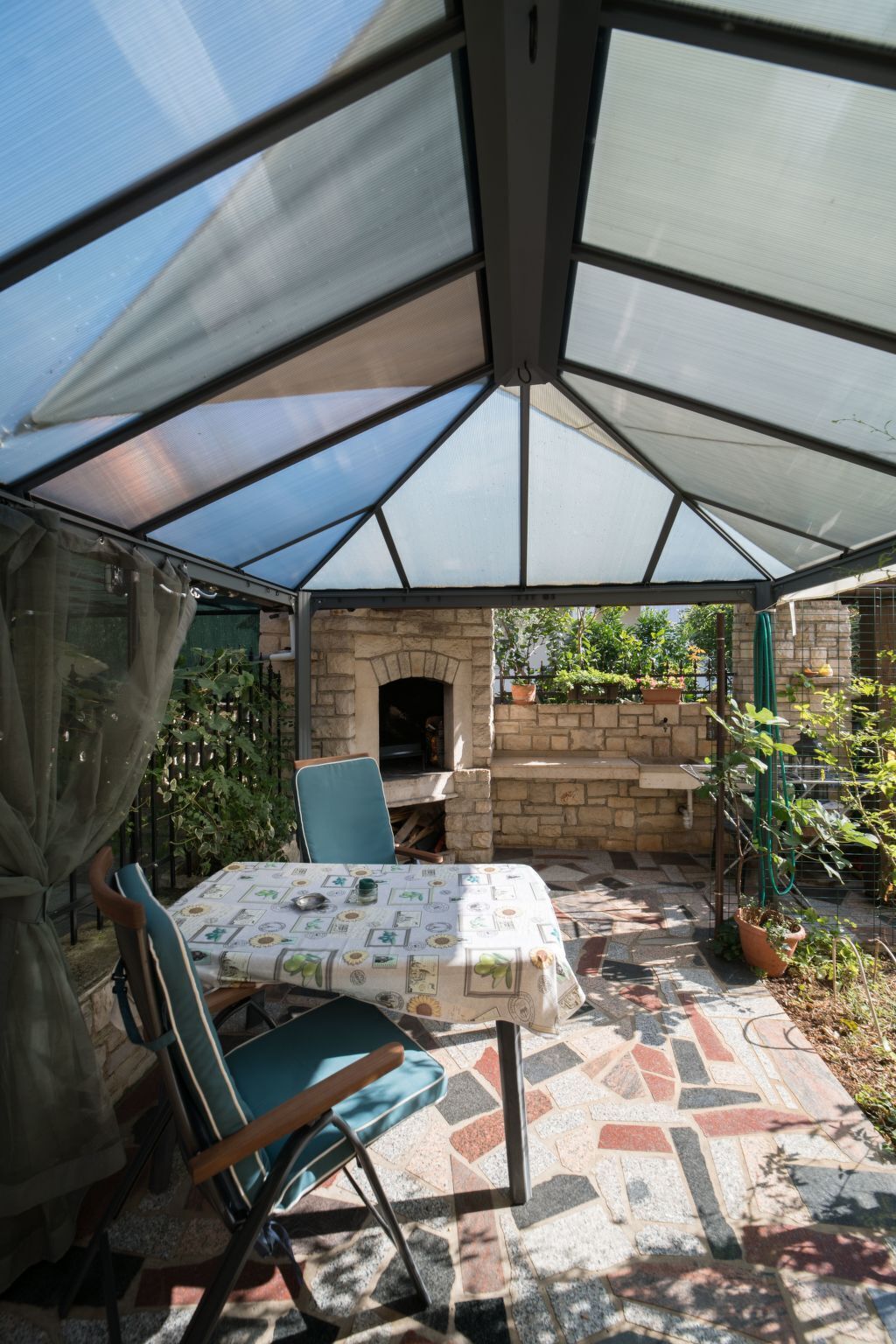 Un patio couvert avec une table et des chaises, un four en briques et des plantes en pot.