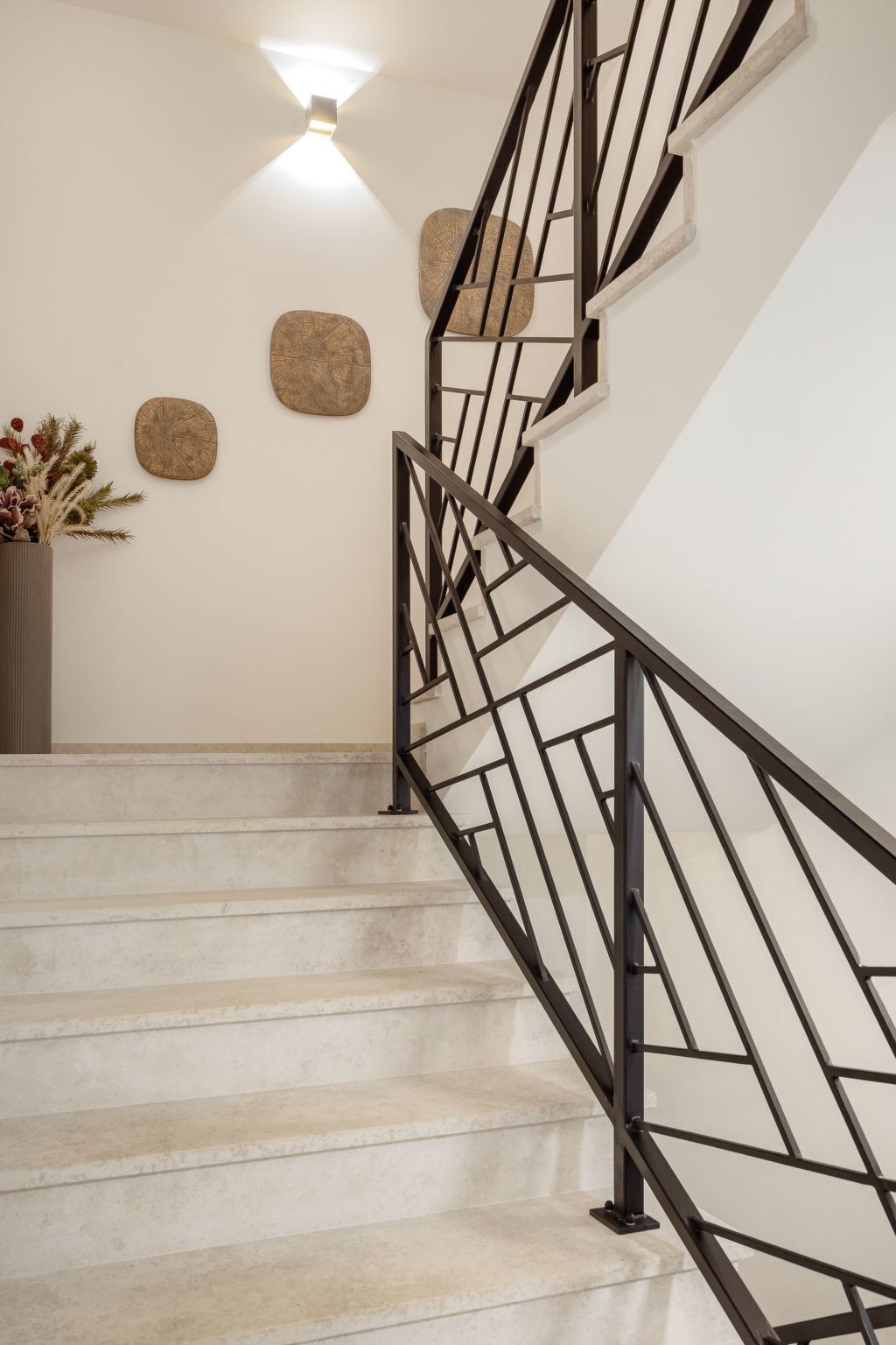 A staircase with a black metal railing, beige steps, and decorative wall art.