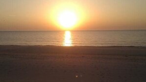 Une plage où le soleil se couche à l’horizon.