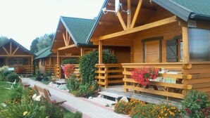 A row of wooden cabins with a porch, surrounded by a garden with various plants and flowers. - in Rusinowo mit Terrasse und Garten by Interhome (Rusinowo)