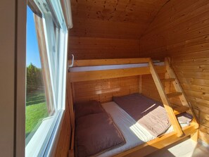 A small, wooden cabin room with a bunk bed and a window overlooking a grassy area. - "New 5" with Infinity-Pool by Interhome (Rusinowo)