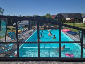 A swimming pool with clear blue water, surrounded by lounge chairs and inflatable toys. - "New 5" with Infinity-Pool by Interhome (Rusinowo)