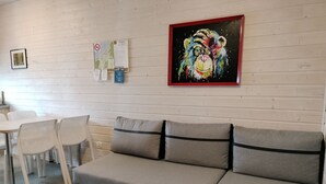 A modern living room with a grey sofa, white chairs, a small table, and a colorful painting on the wall. - Trebor"-Häuser in einem eingezäunten Gebiet by Interhome (Miedzyzdroje)