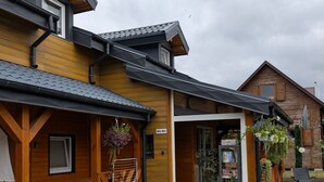 A wooden building with a covered entrance, a small outdoor seating area, and a paved walkway leading to the entrance. - Trebor"-Häuser in einem eingezäunten Gebiet by Interhome (Miedzyzdroje)