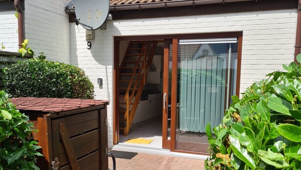 A residential building with a wooden gate, a satellite dish, and a staircase leading to a sliding glass door. - Vacation home House by Interhome (Bredene)