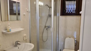 A bathroom with a glass-enclosed shower, a sink, a toilet, and a mirror. - Vacation home House by Interhome (Bredene)