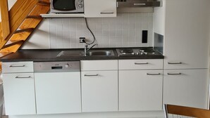 A kitchen with white cabinets, a microwave, a stove, and a sink. - Vacation home House by Interhome (Bredene)