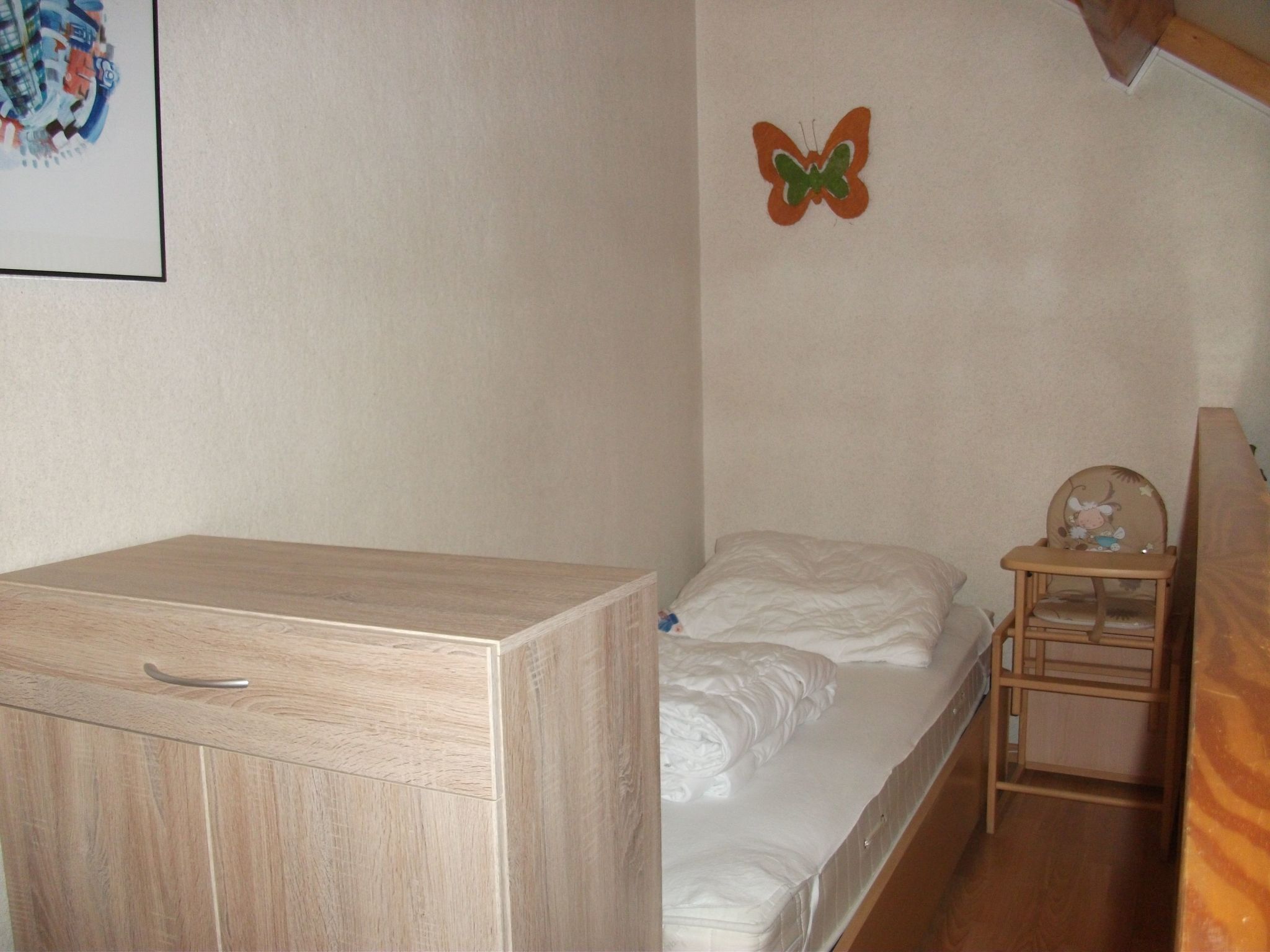 Ein Schlafzimmer mit einem Bett, einem Holzschrank und einem kleinen Nachttisch.