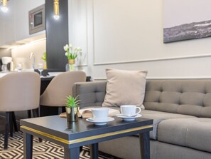 A modern hotel room with a sofa, a small table with a cup and saucer, a plant, and a microwave in the background. - Stilvoll eingerichtete Ferienwohnung am Meer by Interhome (Swinoujscie)