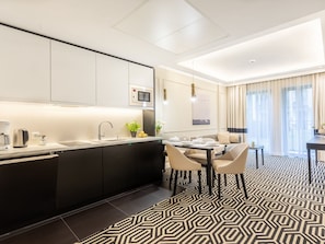A modern kitchen with a built-in oven, a coffee machine, and a sink. There is a dining area with a table and chairs, and a patterned floor. - Stilvoll eingerichtete Ferienwohnung am Meer by Interhome (Swinoujscie)
