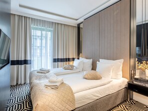 A hotel room with a large bed, a TV, a bedside table with books, and a window with curtains. - Stilvoll eingerichtete Ferienwohnung am Meer by Interhome (Swinoujscie)