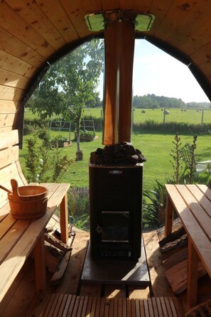A wooden cabin with a Harvia wood stove, wooden benches, and a view of a green field. - Relax’n’Spa by Interhome (Stepnica)