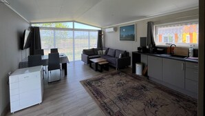 A modern living room with a sofa, a dining table, and a kitchen area. - Haus Kranich by Interhome (Nowe Warpno)