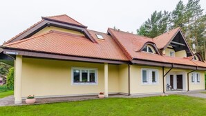 A two-story house with a red-tiled roof, a covered porch, and a well-maintained lawn. - "Apartment4" mit Garten by Interhome (Rowy)
