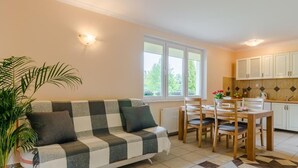 A cozy living room with a checkered sofa, a dining table with chairs, and a kitchen area with cabinets. - "Apartment4" mit Garten by Interhome (Rowy)