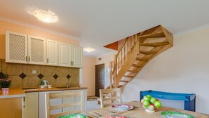 A compact kitchen with a wooden staircase, a dining table set with plates and fruits, and a small sink. - "Apartment4" mit Garten by Interhome (Rowy)