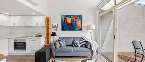 A modern living room with a grey sofa, a cowhide rug, and a painting on the wall.