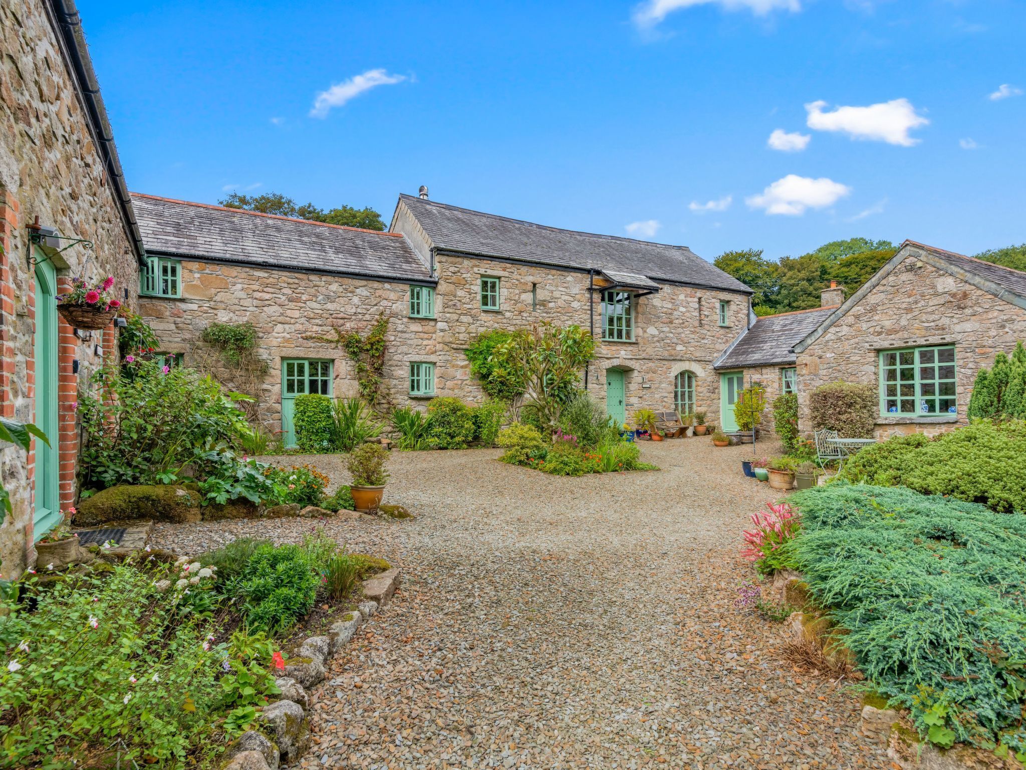 A stone building with multiple windows and a gravel path leading to a door.