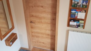 Een houten deur met een metalen handgreep, een klein houten plankje en een prikbord met diverse spullen erop bevestigd.