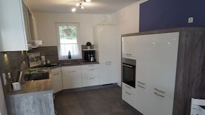 A modern kitchen with white cabinets, a built-in oven, and a coffee maker. - Traumbrise by Interhome (Rerik)