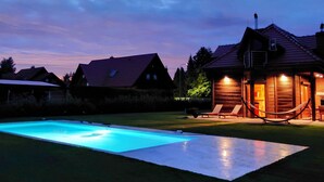 A wooden cabin with a swimming pool, surrounded by a lawn and other houses. - mit Schwimmbad by Interhome (Krokowa)