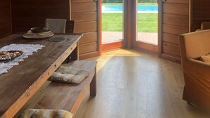 A wooden cabin interior with a dining table, bench seating, and a view of a swimming pool outside. - mit Schwimmbad by Interhome (Krokowa)