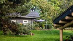 Ein Haus mit einem geneigten Dach, umgeben von einem gepflegten Rasen und Bäumen.