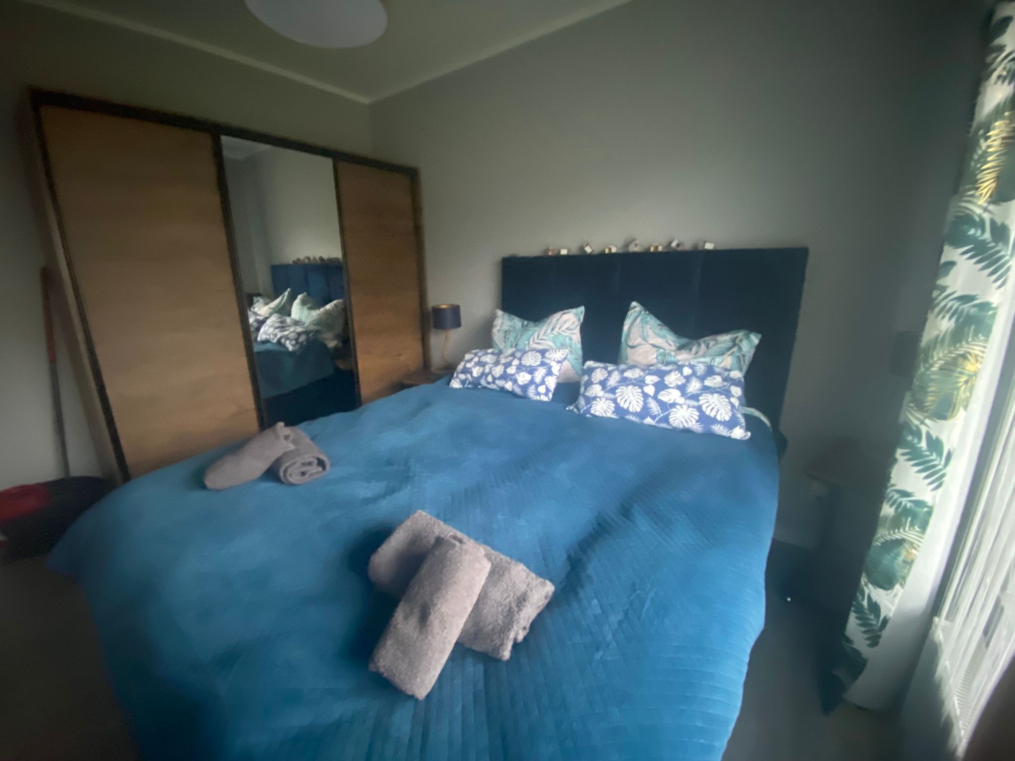 Un dormitorio con una cama grande, un armario y un espejo.