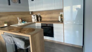 Una cocina moderna con una isla de madera, taburetes de bar, luces colgantes y armarios empotrados.