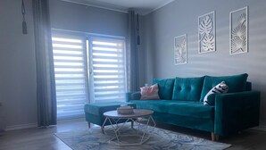Una sala de estar moderna con un sofá azul verdoso, una mesa de centro redonda y una alfombra estampada.